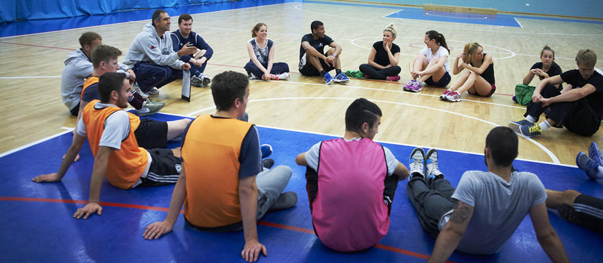 Sports students sit in a circle in a sports hall