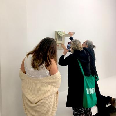 Three people in a gallery at a wall