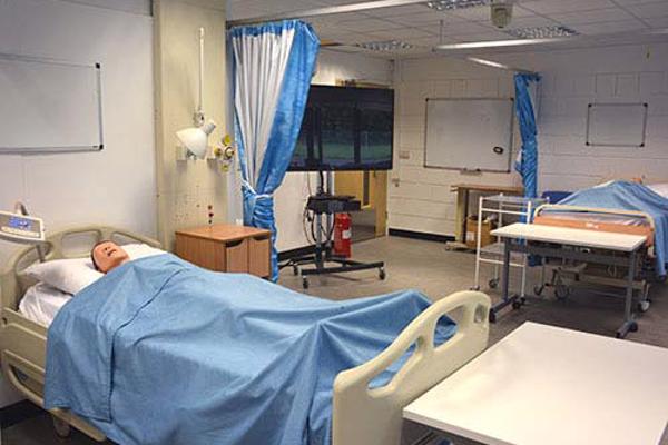 A sim man dummy lies in a hospital bed in a clinical skills room used on our nursing degree.