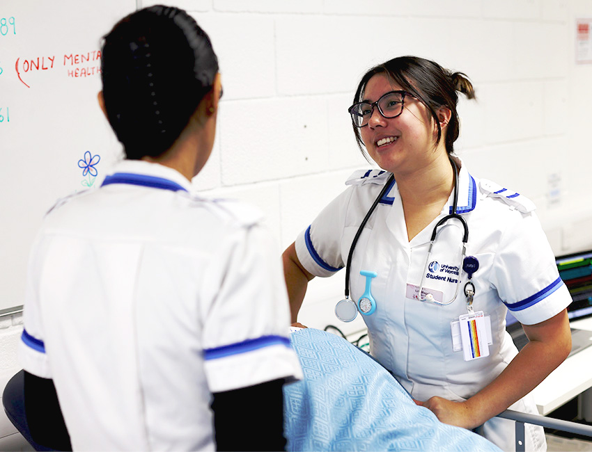 Two students in nursing uniform working in a simulated hospital environment