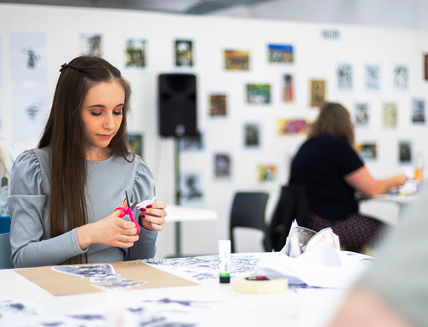 Student cutting out an illustration in the art studio