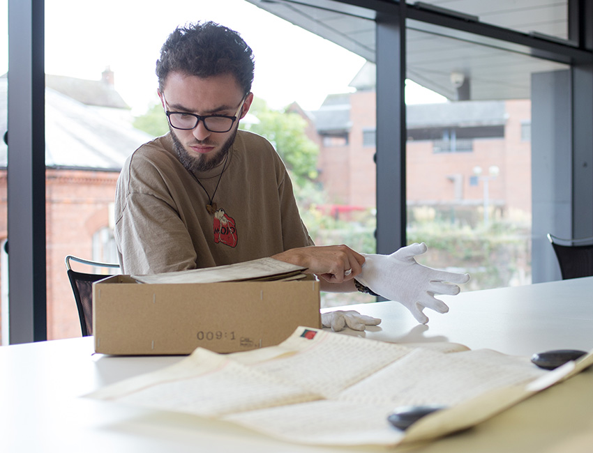 A student pulling on gloves to handle a historic document