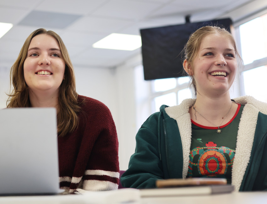 Two students smiling during a lecture