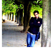 man in a black top leaning against a tree