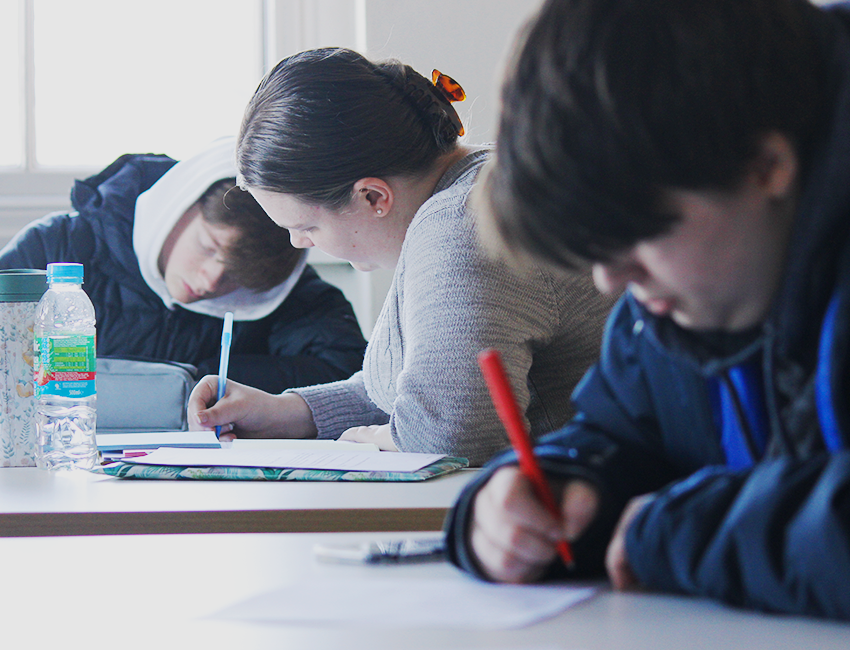Students at a table writing notes on printed out screenplays