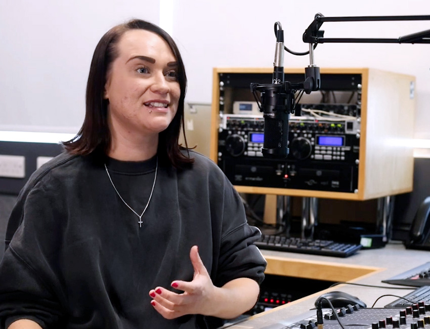 Journalist talking into a microphone in a recording booth