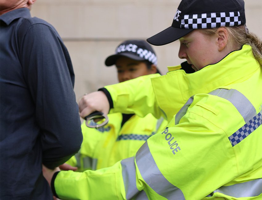 Two policing students practicing arrest techniques on a lecturer