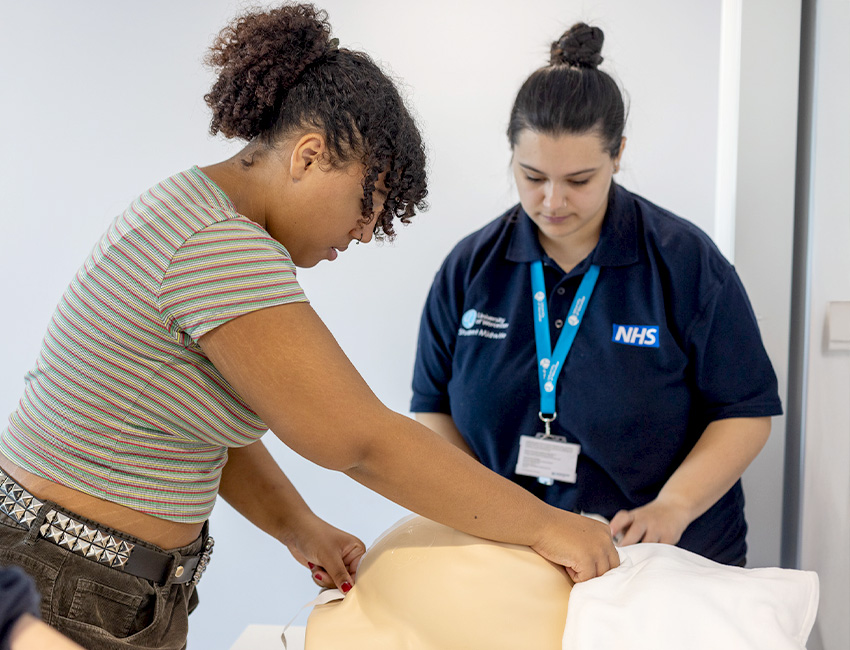 A student midwife learning clinical skills on a medical manikin