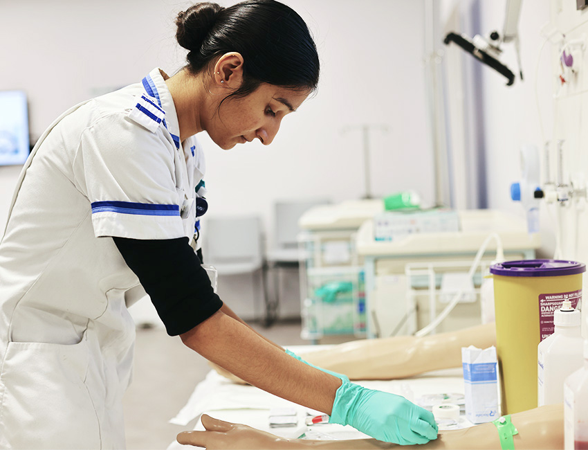Student nurse using a model arm to practice taking a blood test