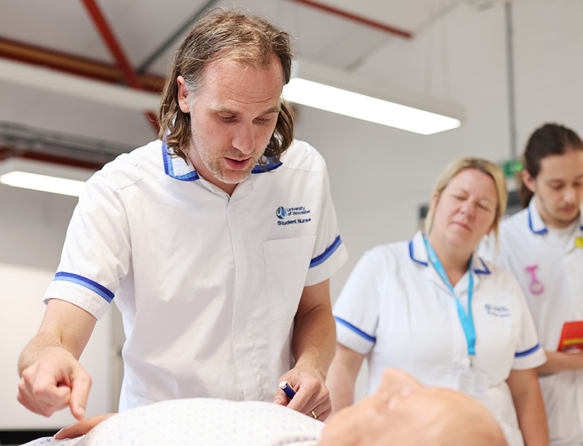 A group of nursing students practicing their clinical skills on a medical manikin