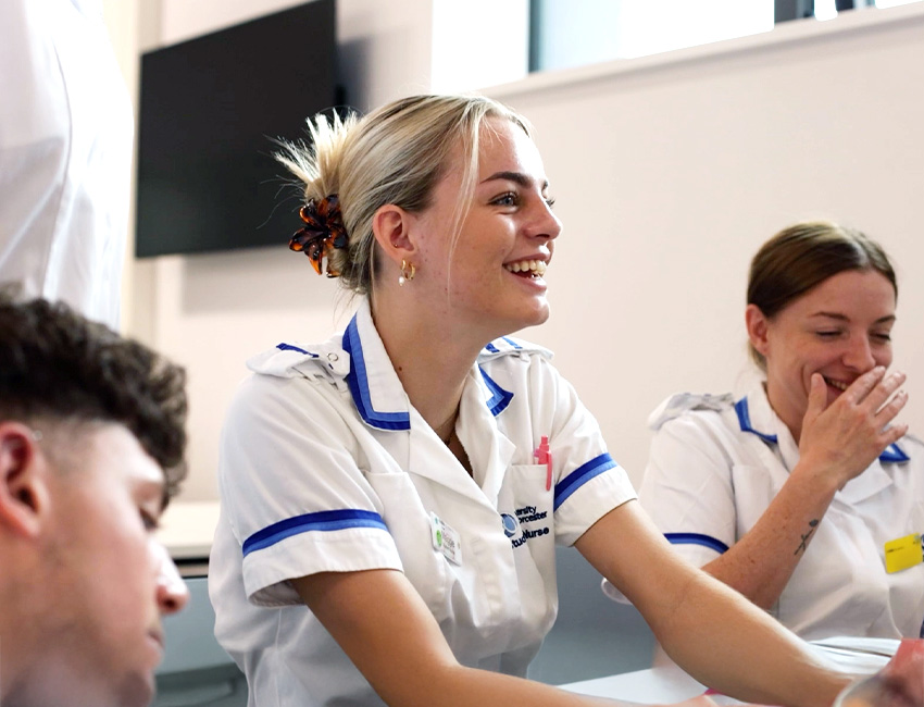 Three nursing students smiling during a skills simulation