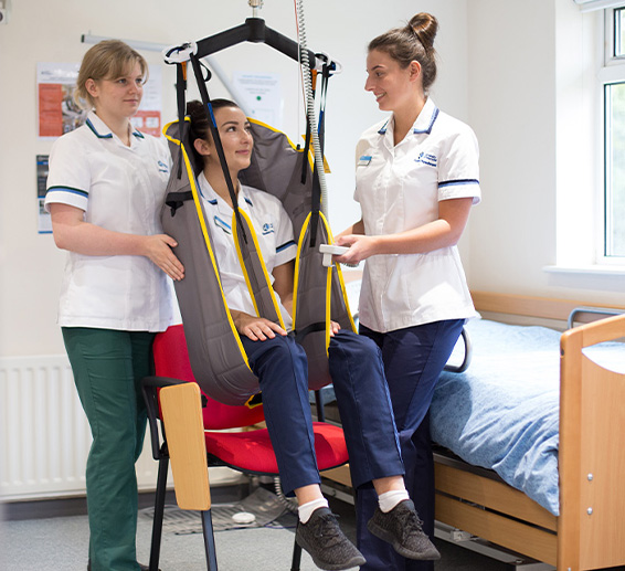 Thee occupational therapy students practicing with a chair hoist