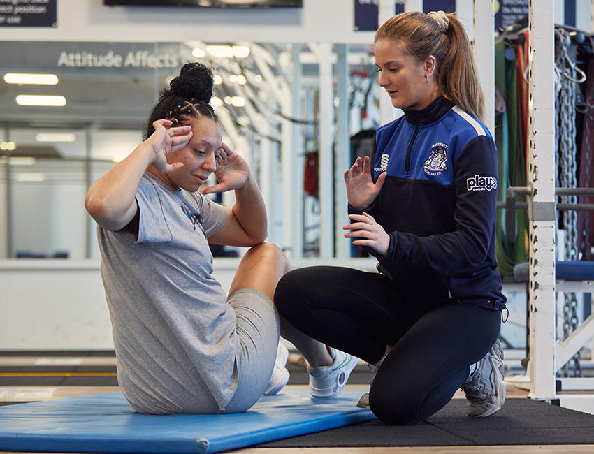 A gym professional helping someone with their workout