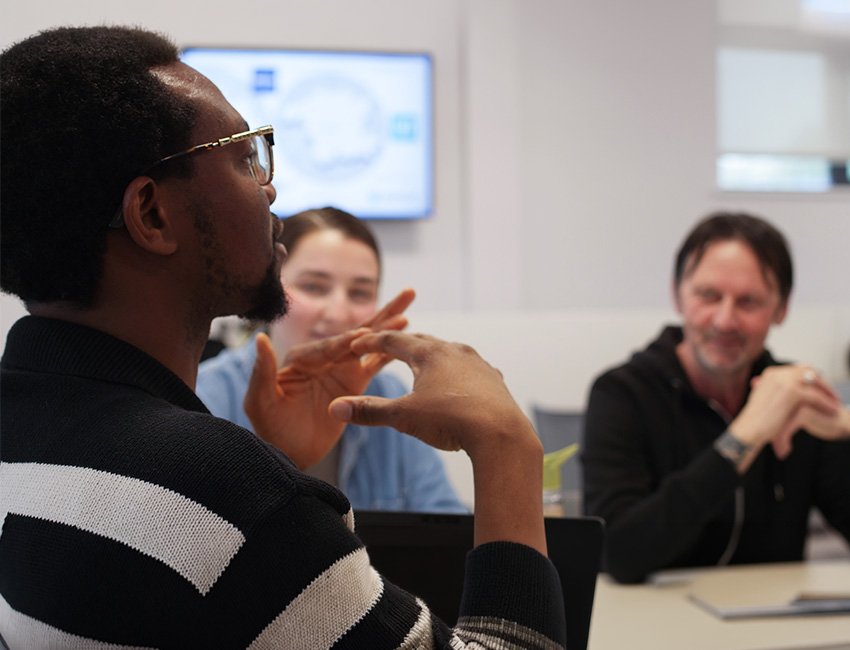 Two students in the background listening to student in foreground sharing their thoughts in a classroom