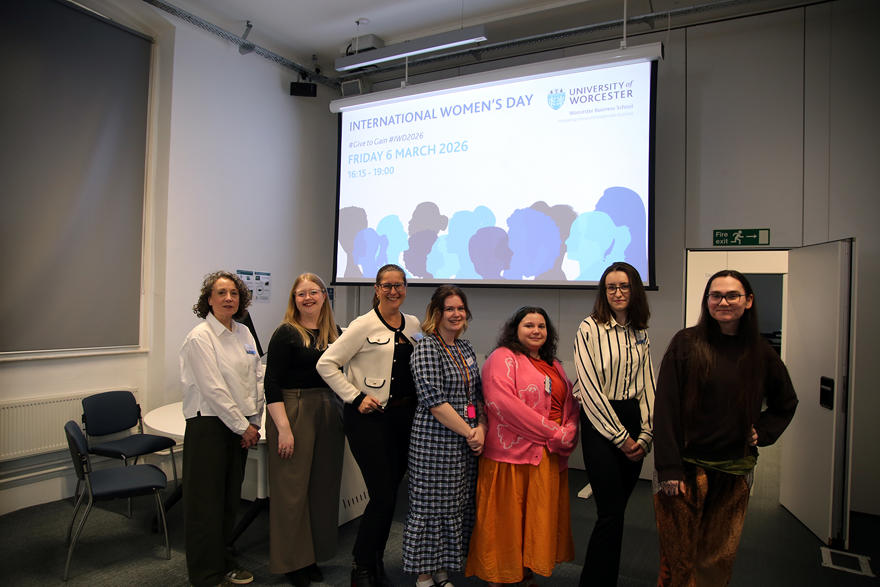 Speakers at the event pose in a row with the title of the talk behind them