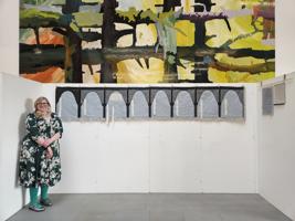 Lucie Bea Dutton poses next to a long stitchwork depicting people who loved Cromwell
