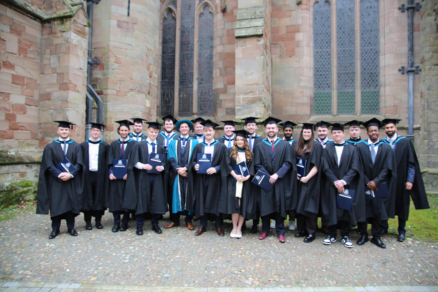 The whole Sports Performance Analysis cohort poses outside Worcester Cathedral in their graduation robes