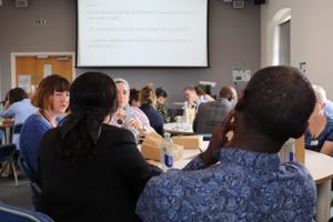 A group of people seated around tables talking together