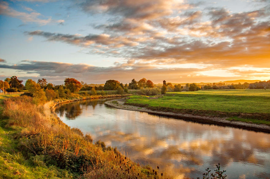 Looking across River Wye and Wye Valley at sunrise autumn colurs sky reflected in the water