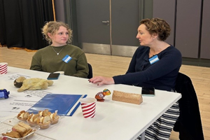Two people sitting at a table during Storytelling Activity about toys visible on the table.
