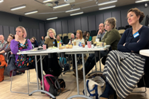 Attendees around tables listening to session being delivered at Transformative Tales Event