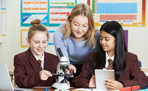 A teacher is helping two female students