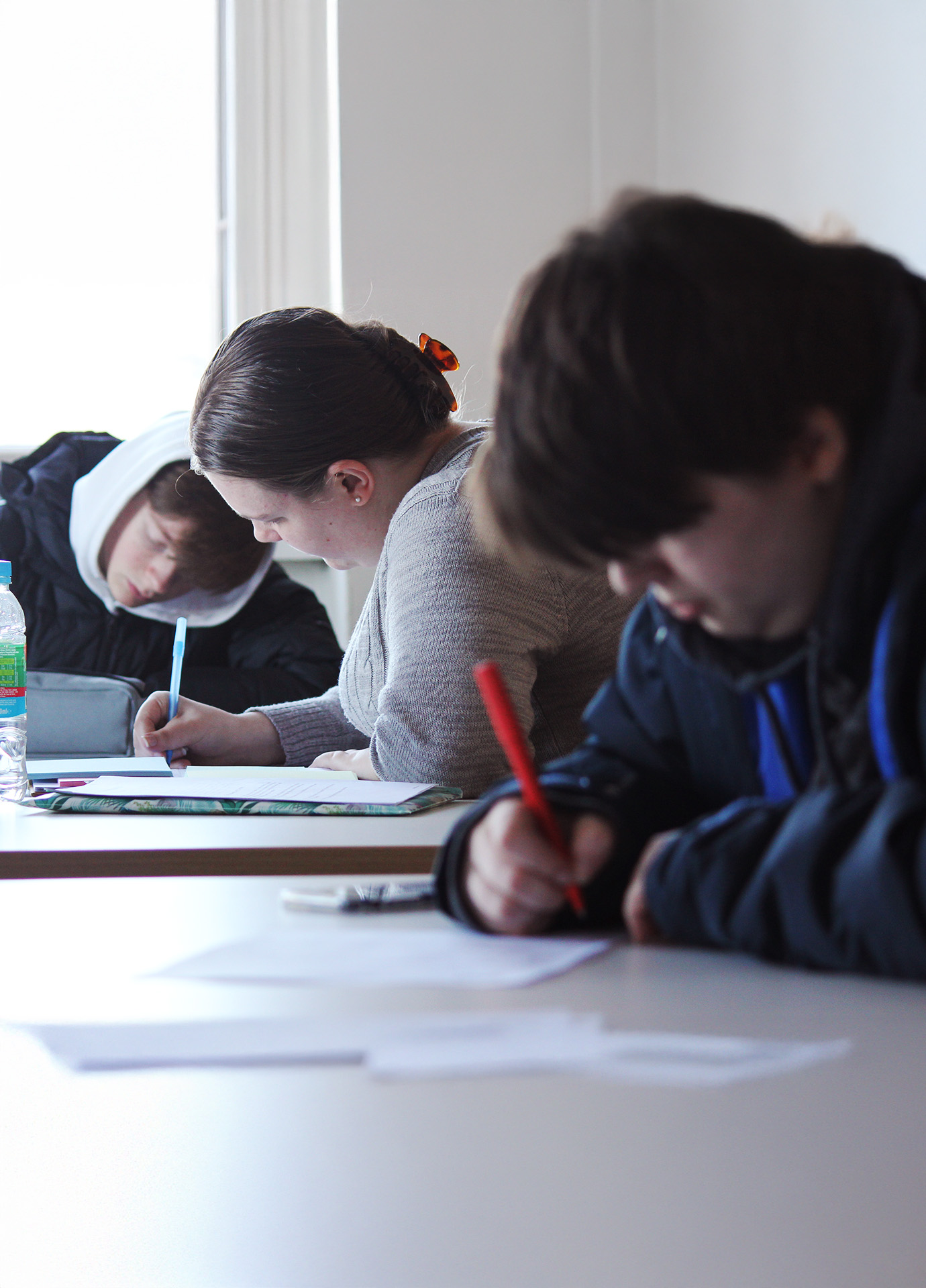 Students writing on paper with pens