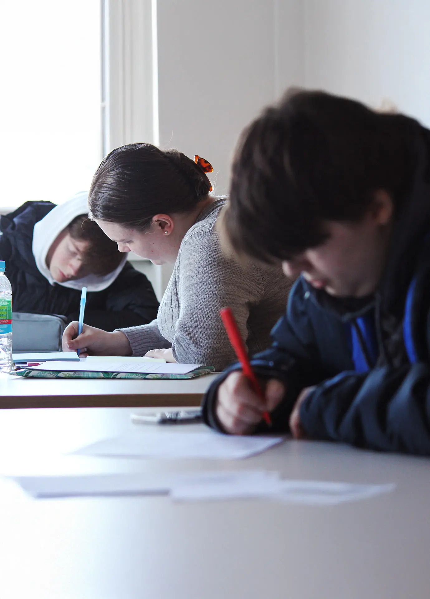 Students writing on paper with pens