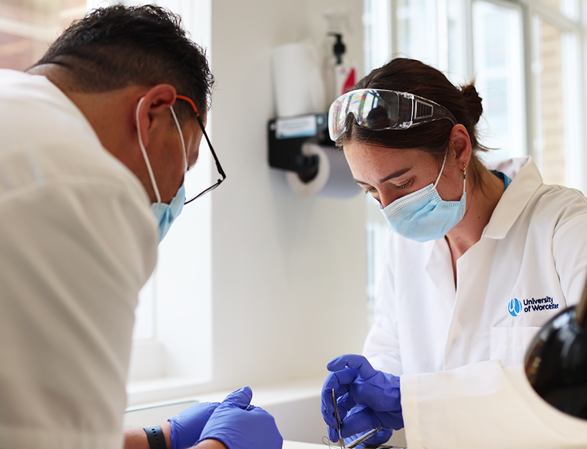 Lecturer providing individual support to student in a lab. Both wearing lab coats