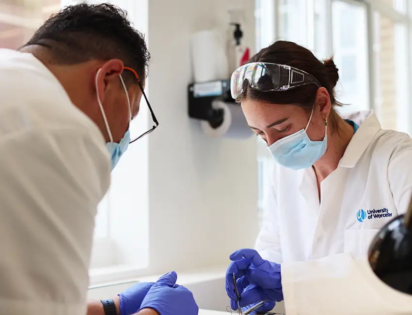 Lecturer providing individual support to student in a lab. Both wearing lab coats