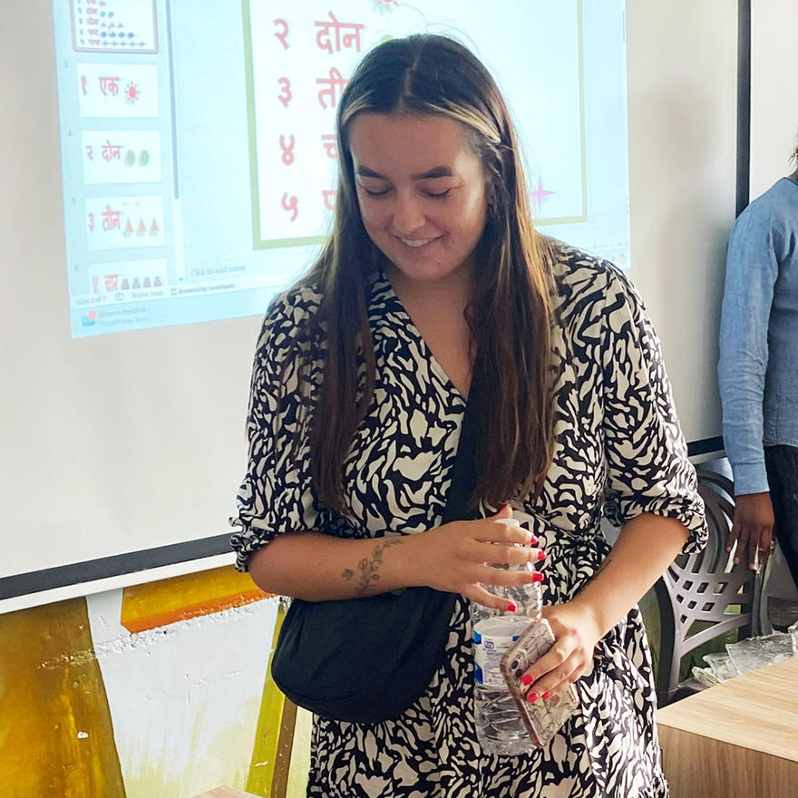 Tea Evans looking over a student's work in a classroom in India