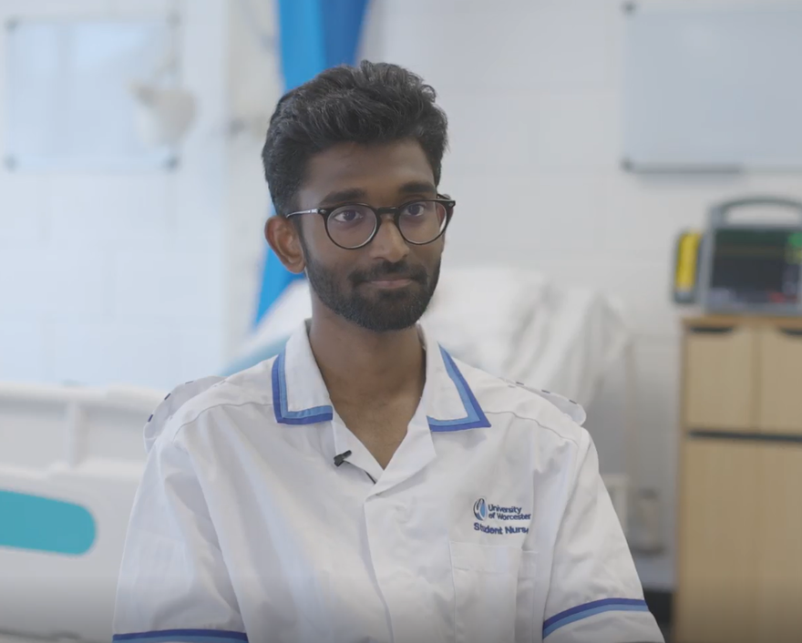 Abit Madukkakkuzhy George sits in a chair in a clinical setting in his nursing uniform