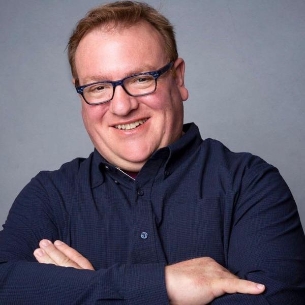 Adrian Hobart smiles as he poses for this head shot style photo