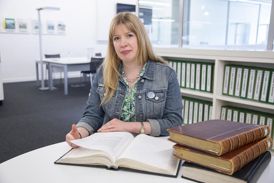 Dr Anna Muggeridge poses with old books in the library