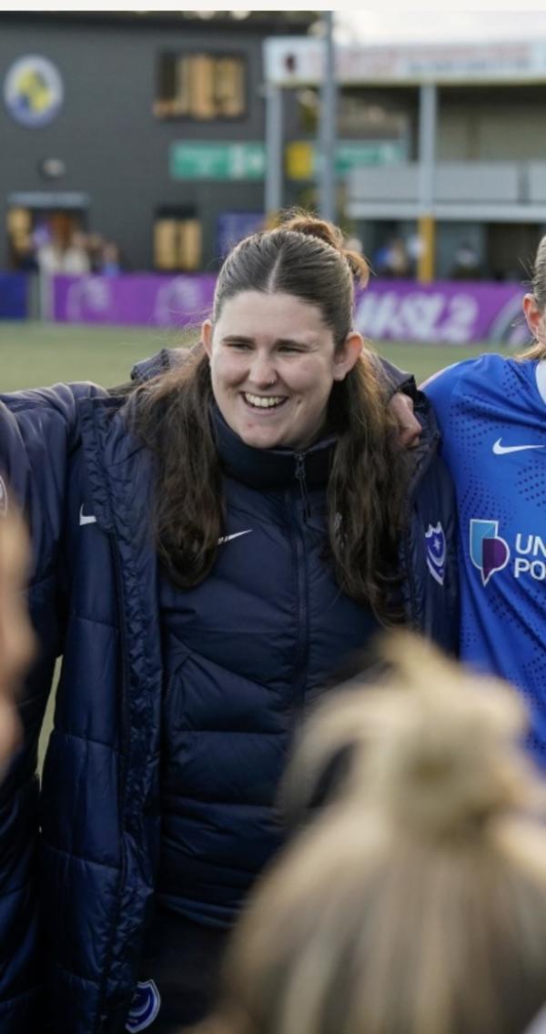 A  photo of Beca Jones in a team huddle on a pitch