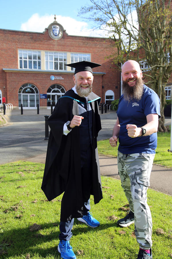 Chris Garrett and Justyn Surrall pose in their running kit in front of the University's entrance