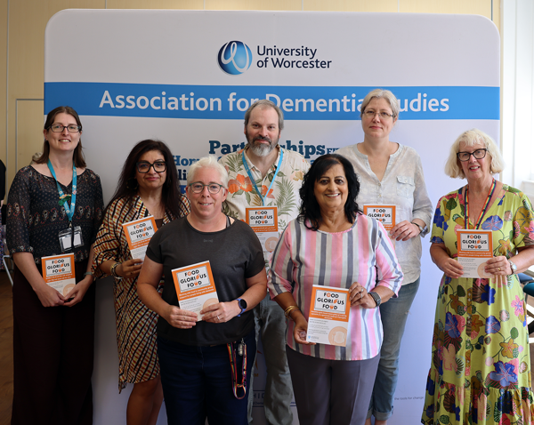 7 people pose for the camera holding pamphlets