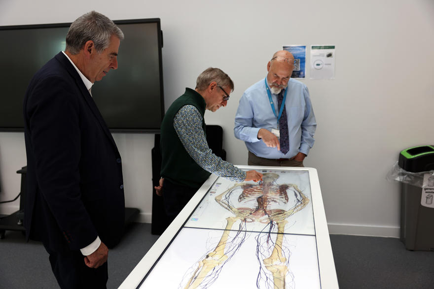 three people look at a touch screen medical computer