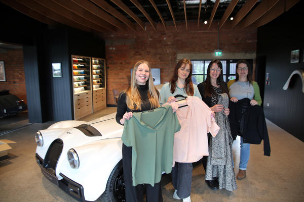 The team at Morgan pose with their donations by a Morgan sports car