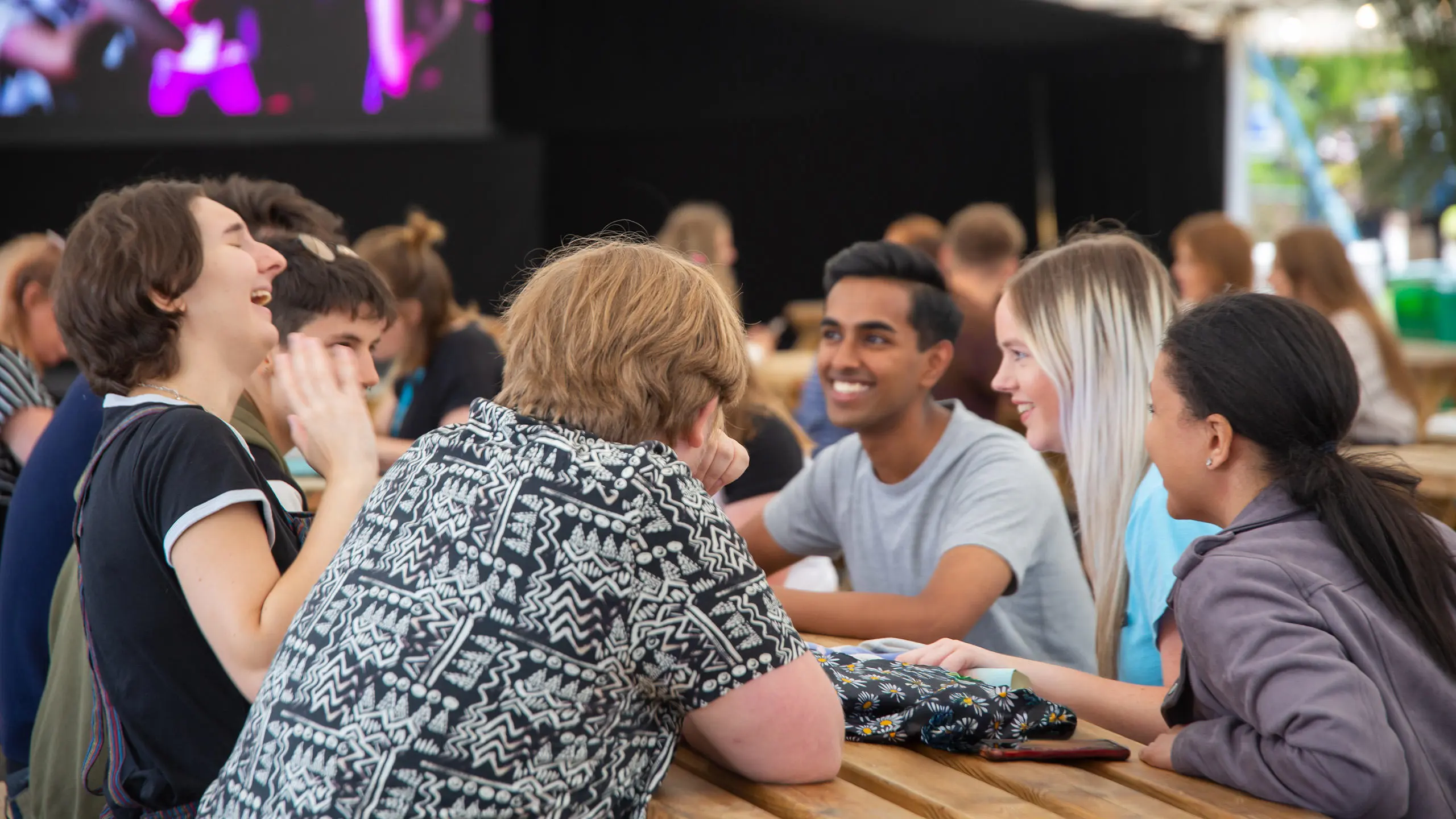 A group of students talking and laughing at a picnic table