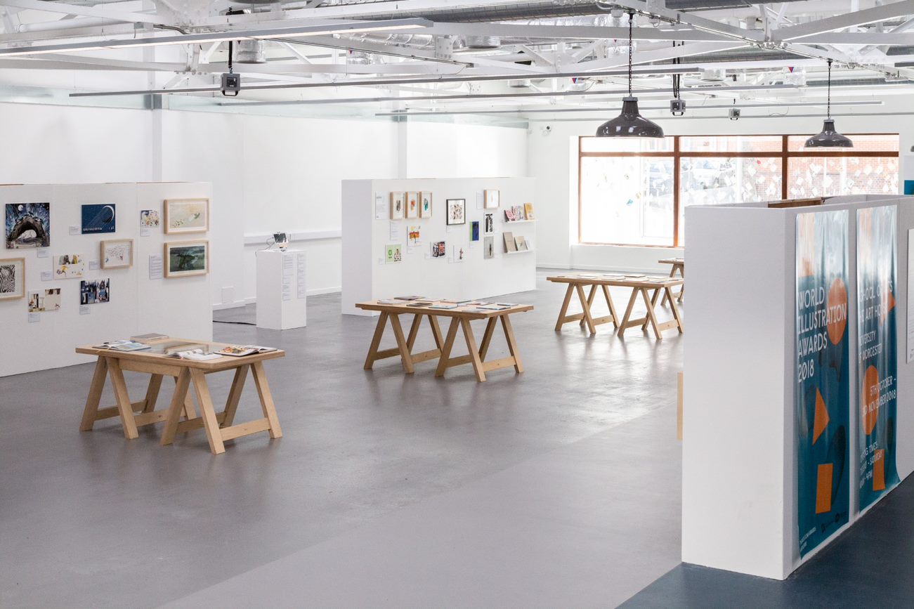 Art House interior. White room with three art display boards and three desks with students art work.