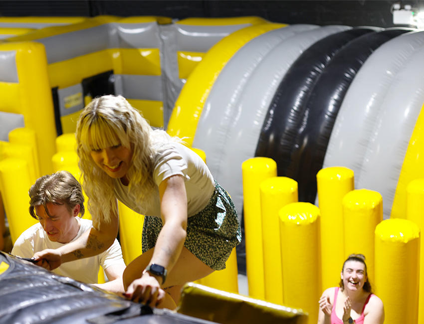 Student climbing up an inflatable wall being cheered on by a friend in the distance