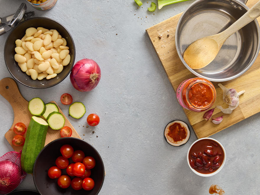 A countertop with saucepans, chopping boards, and vegetables