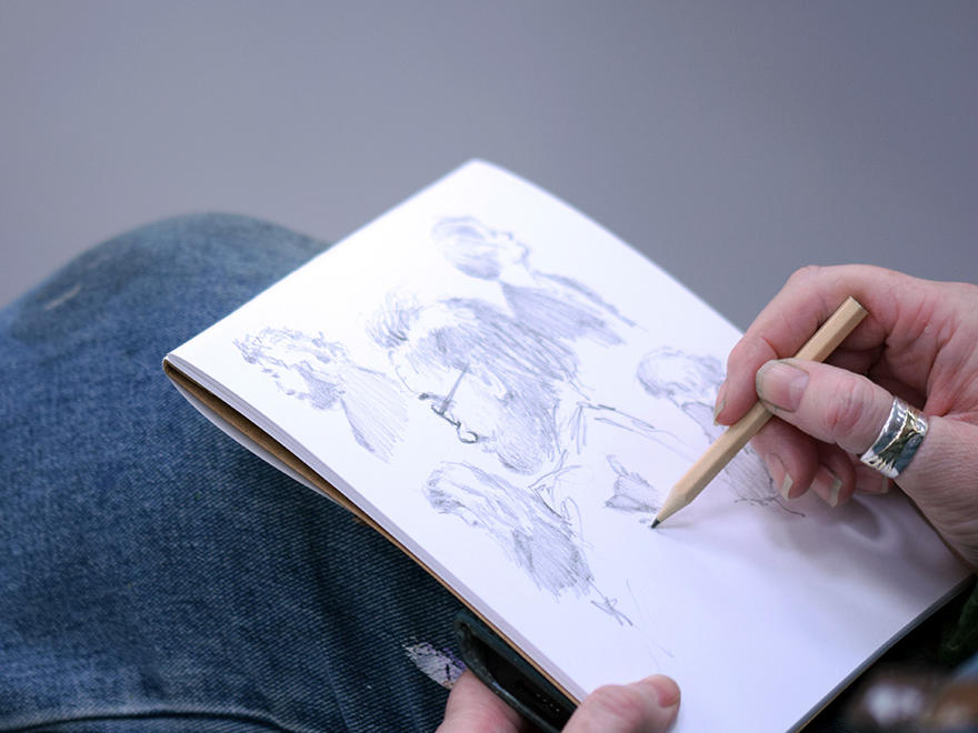 A hand sketching profiles of people