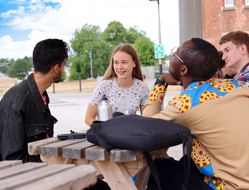 Group of friends sat around a picnic bench having a chat