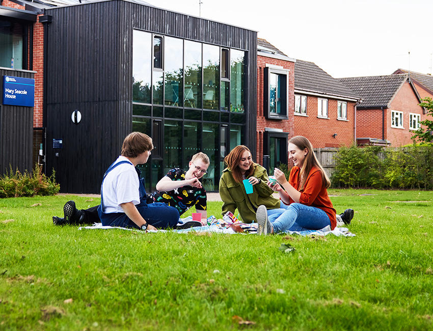 Students enjoying a picnic on the grass  outside accommodation