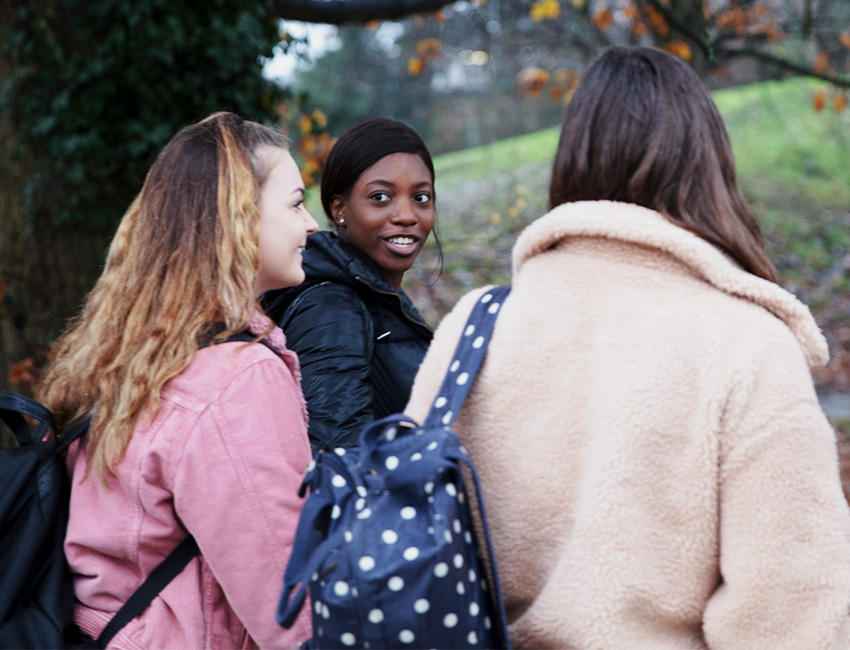 Students walking pased autumnal trees in winter coats