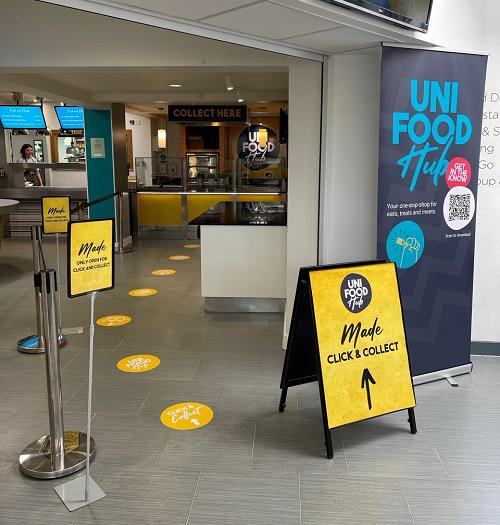 uni food signage with yellow A boards and circular dots that lead to a serving counter