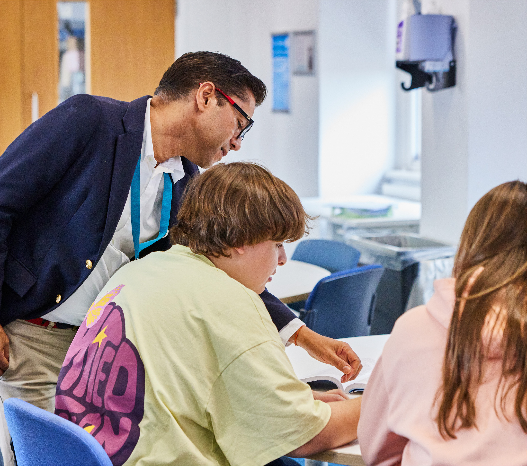 A lecturer leaning over a student at a table to look at their work