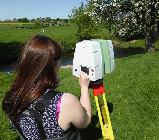 Student using fieldwork equipment next to a stream